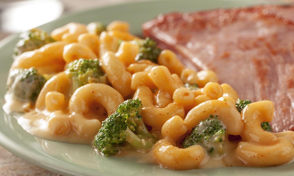 Macaroni and cheese with broccoli served alongside ham
