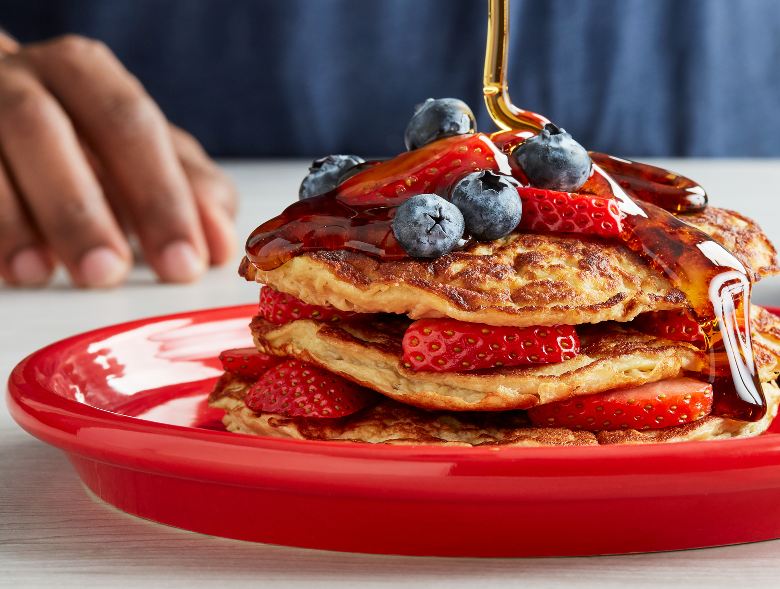 A stack of strawberry protein pancakes drizzled with syrup