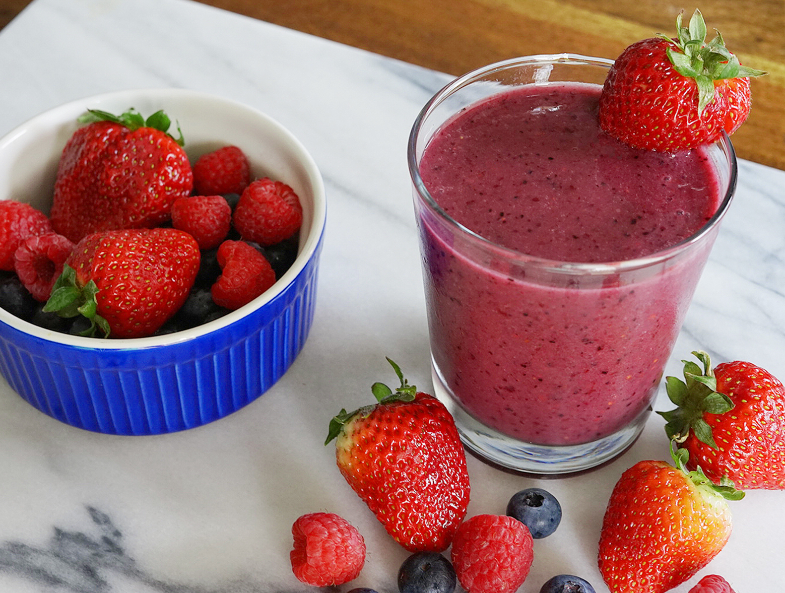 Berry booster protein smoothie in a glass served with strawberries