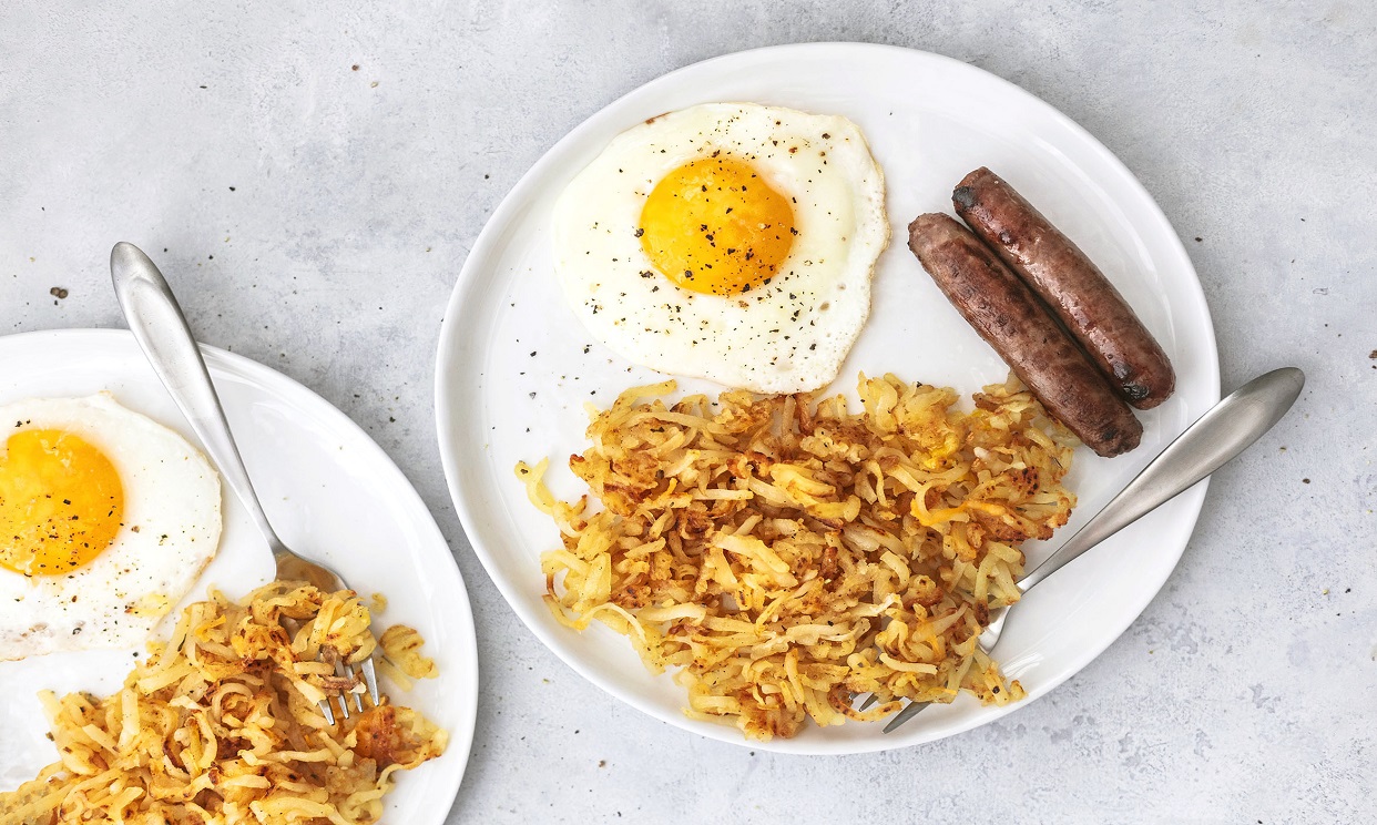 Shredded hash browns, with an over easy egg and two breakfast sausage links