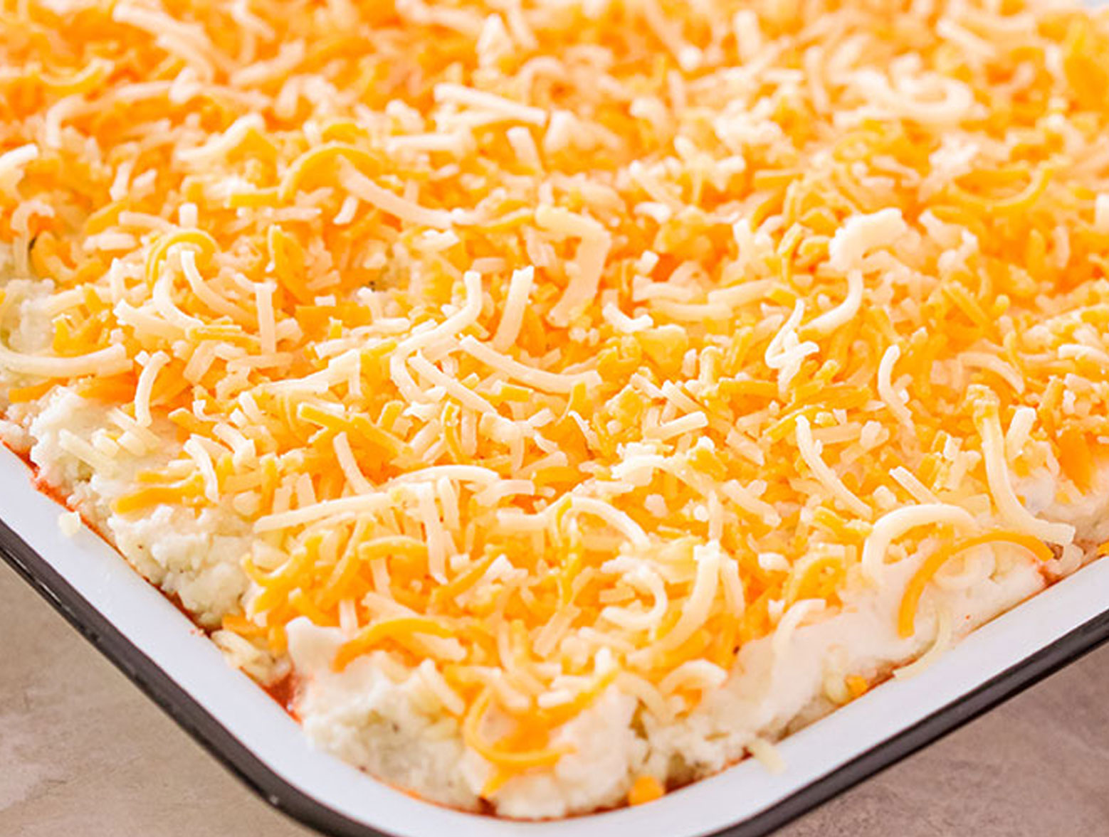 Chili mashed potato casserole covered in shredded cheese