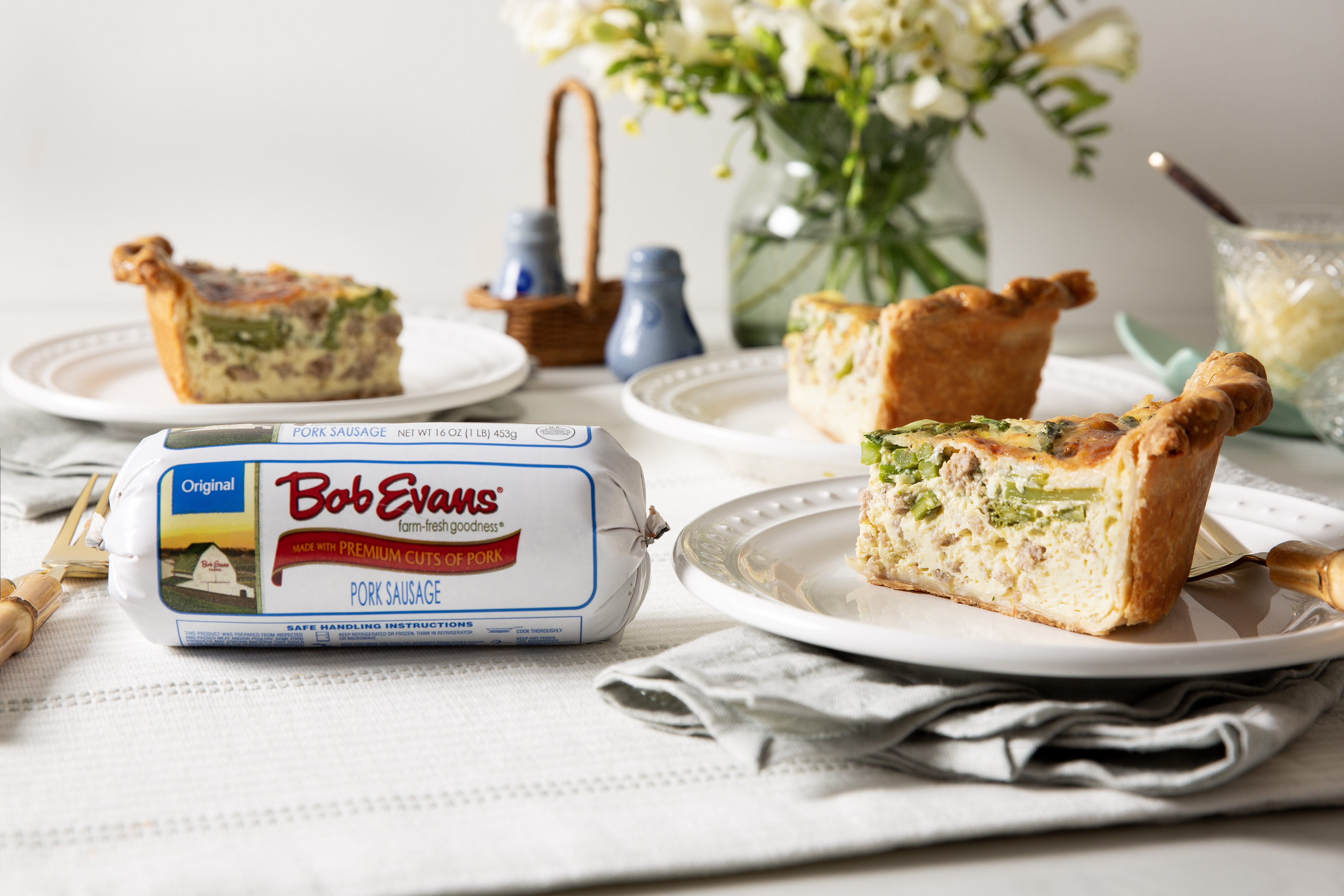 a slice of sausage asparagus quiche next to a roll of Bob Evans Original Sausage